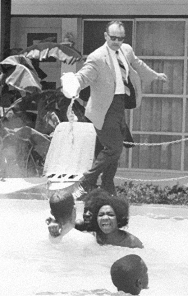 Hotel owner pouring acid in the pool while black people swim in it, ca. 1964.