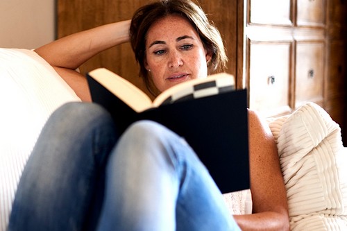 Mature woman reading a book in her sofa